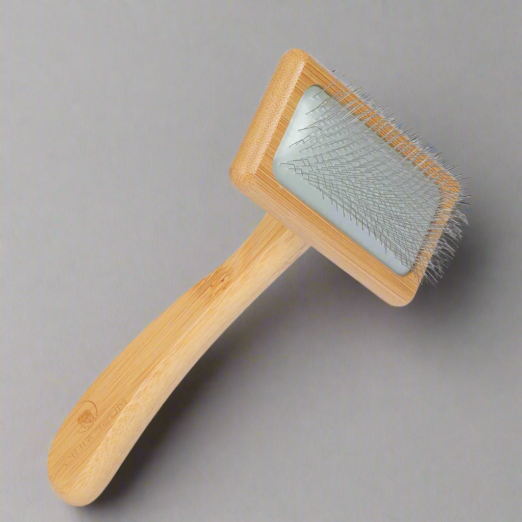 Pet grooming brush with wooden handle and metal bristles on a white background