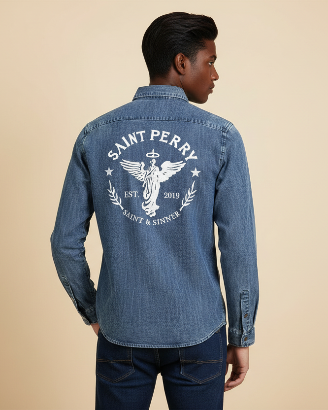 Man wearing a blue denim shirt with 'Saint Perry' logo on the back against a beige background
