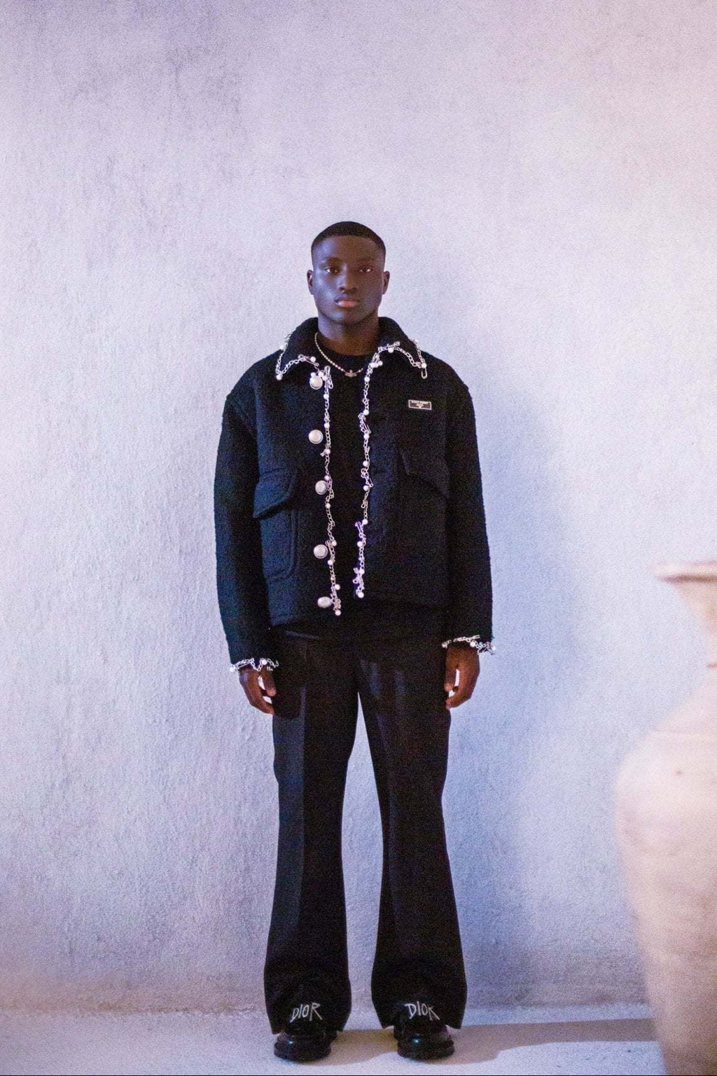 Person wearing a black jacket with white accents in a minimalistic setting