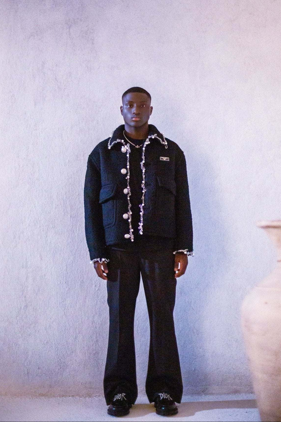 Person wearing a black jacket with white accents in a minimalistic setting