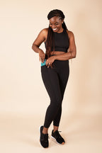Woman wearing black athletic wear on a gray background
